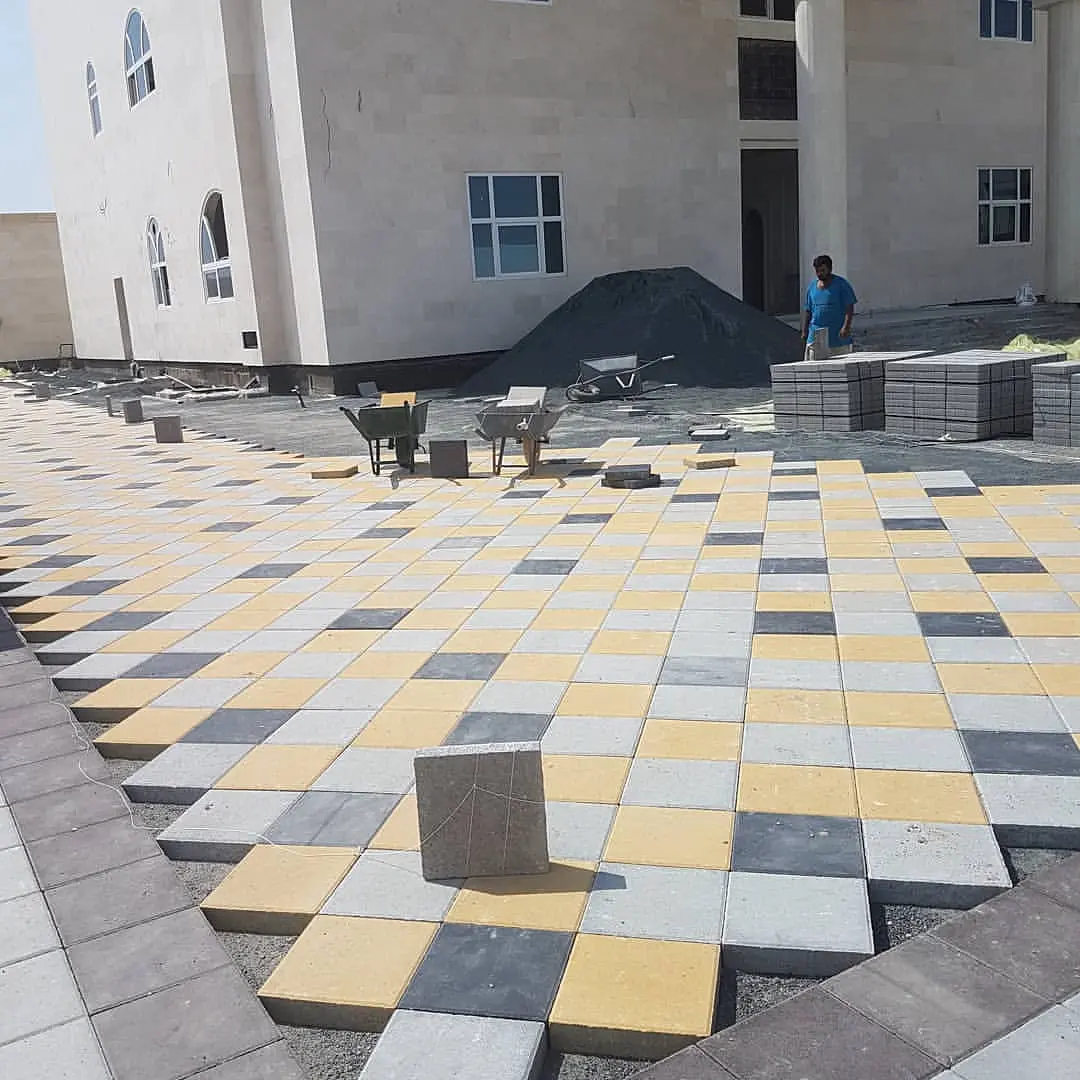Large, square interlocking pavers used as stepping stones across a lawn.